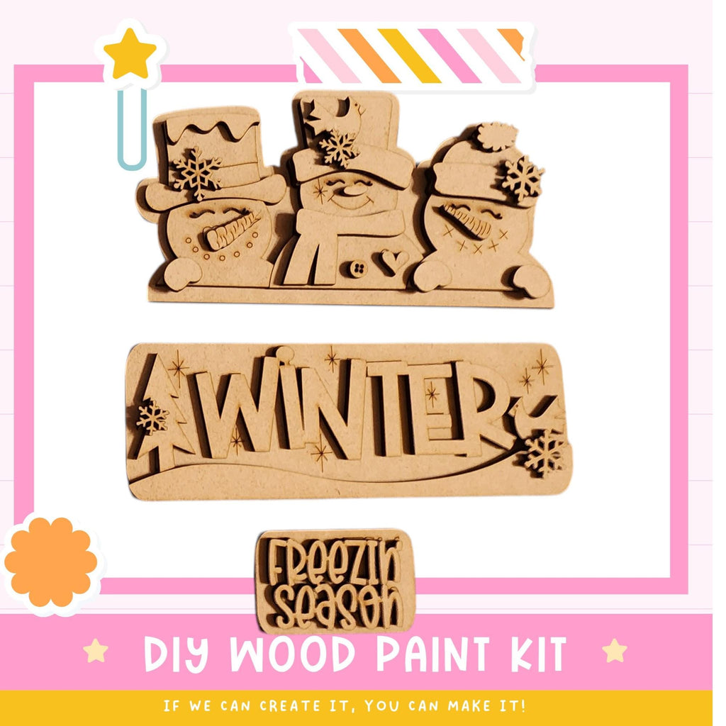 The image is a promotional poster for a DIY wood paint kit, featuring three wooden snowmen and the word "WINTER" written on a wooden block.