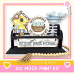 a DIY wood paint kit for creating a welcoming home, including a birdhouse, a sign, and a beaded string.