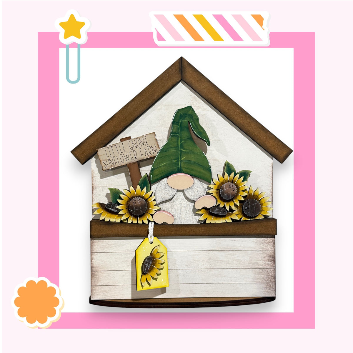 A wooden gnome figurine is displayed in a wooden house-like structure, surrounded by sunflowers and a sign that reads "Little Gnome Sunflower Farm".