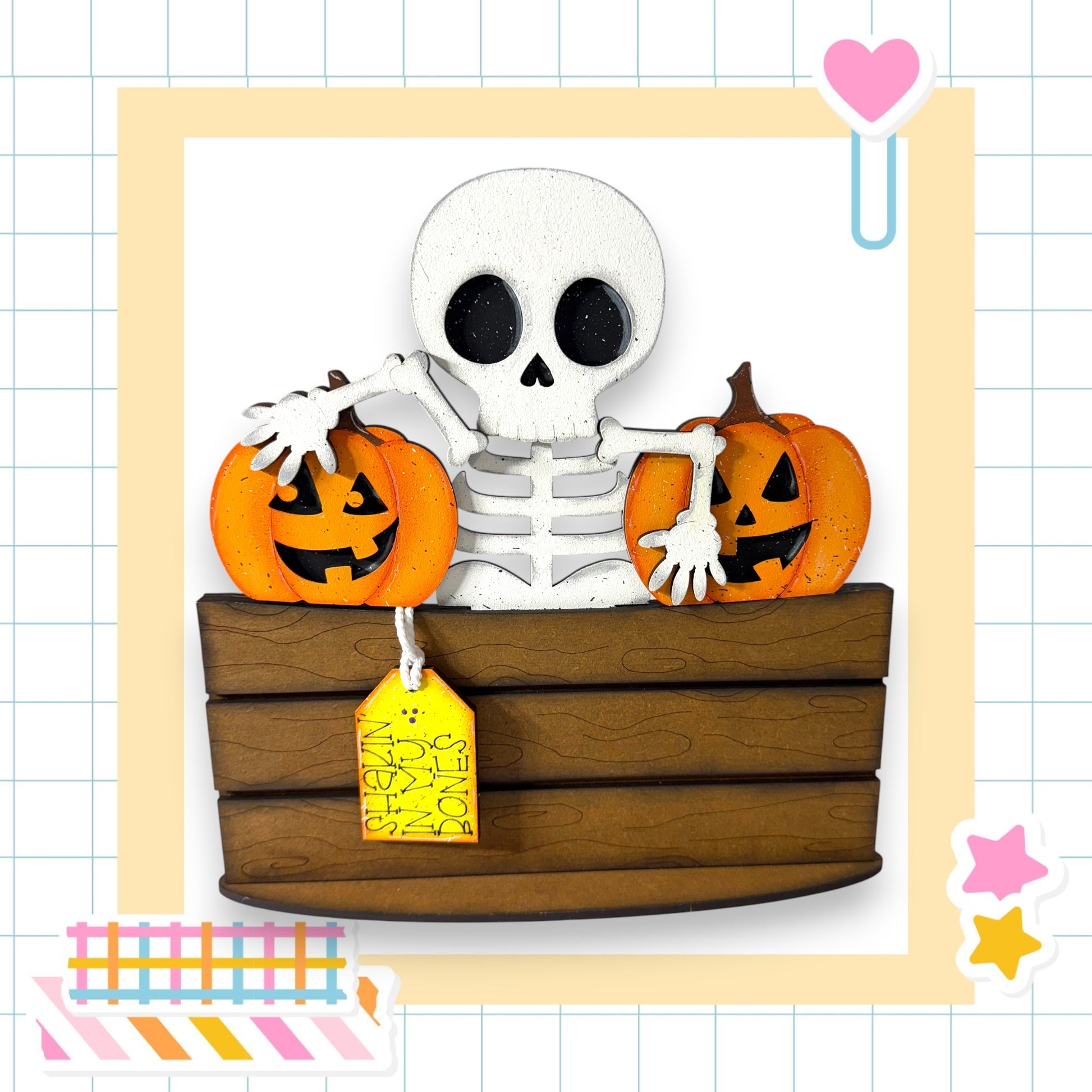 A skeleton holding two carved pumpkins, sitting in a wooden crate, with a yellow tag attached to the crate.
