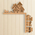 A wooden Christmas-themed decoration with a train and houses on a snowy hill.