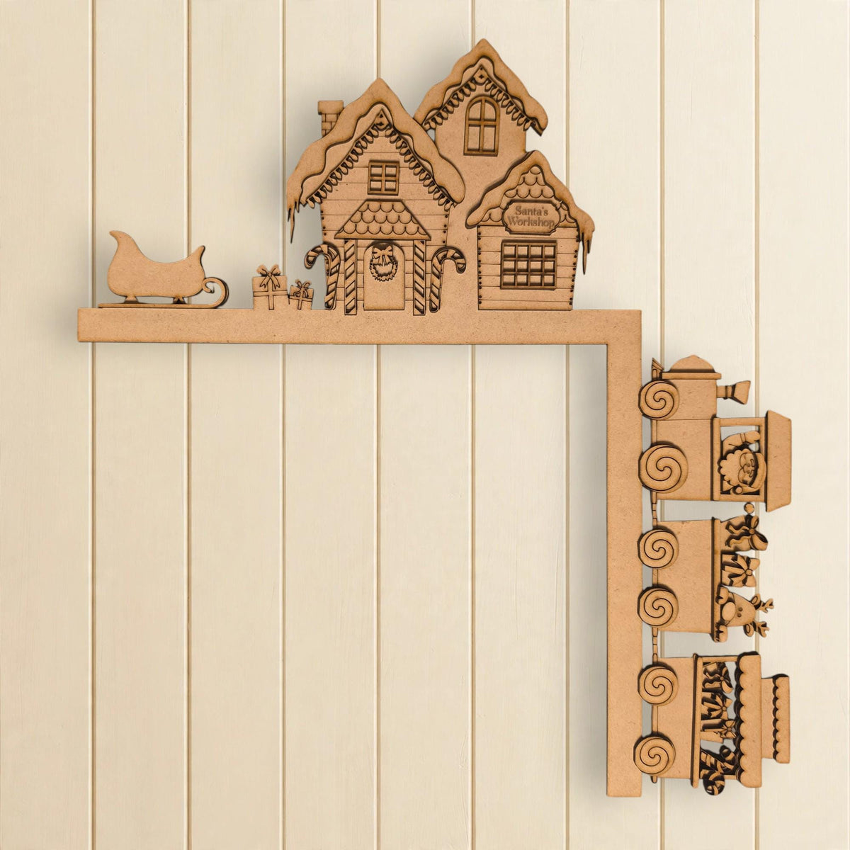 A wooden Christmas-themed decoration with a train and houses on a snowy hill.