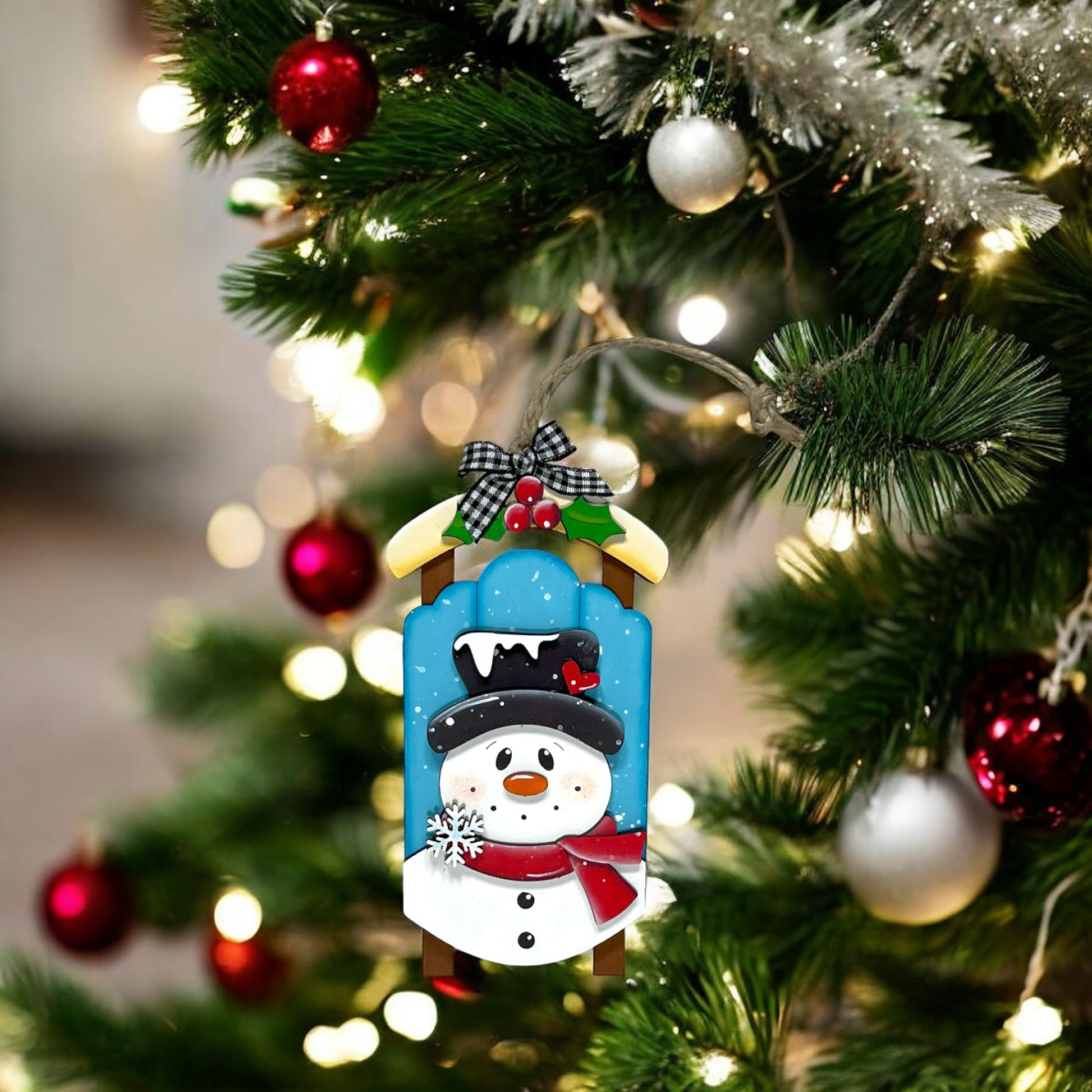 a snowman ornament hanging from a christmas tree