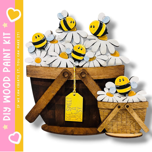 A wooden bucket filled with white daisies and yellow bees, with a yellow tag attached that says "Bee Sweet daisy".