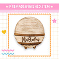 a wooden welcome sign with the word "Welcome" written on it, surrounded by decorative elements such as a heart, a star, and a zigzag pattern.