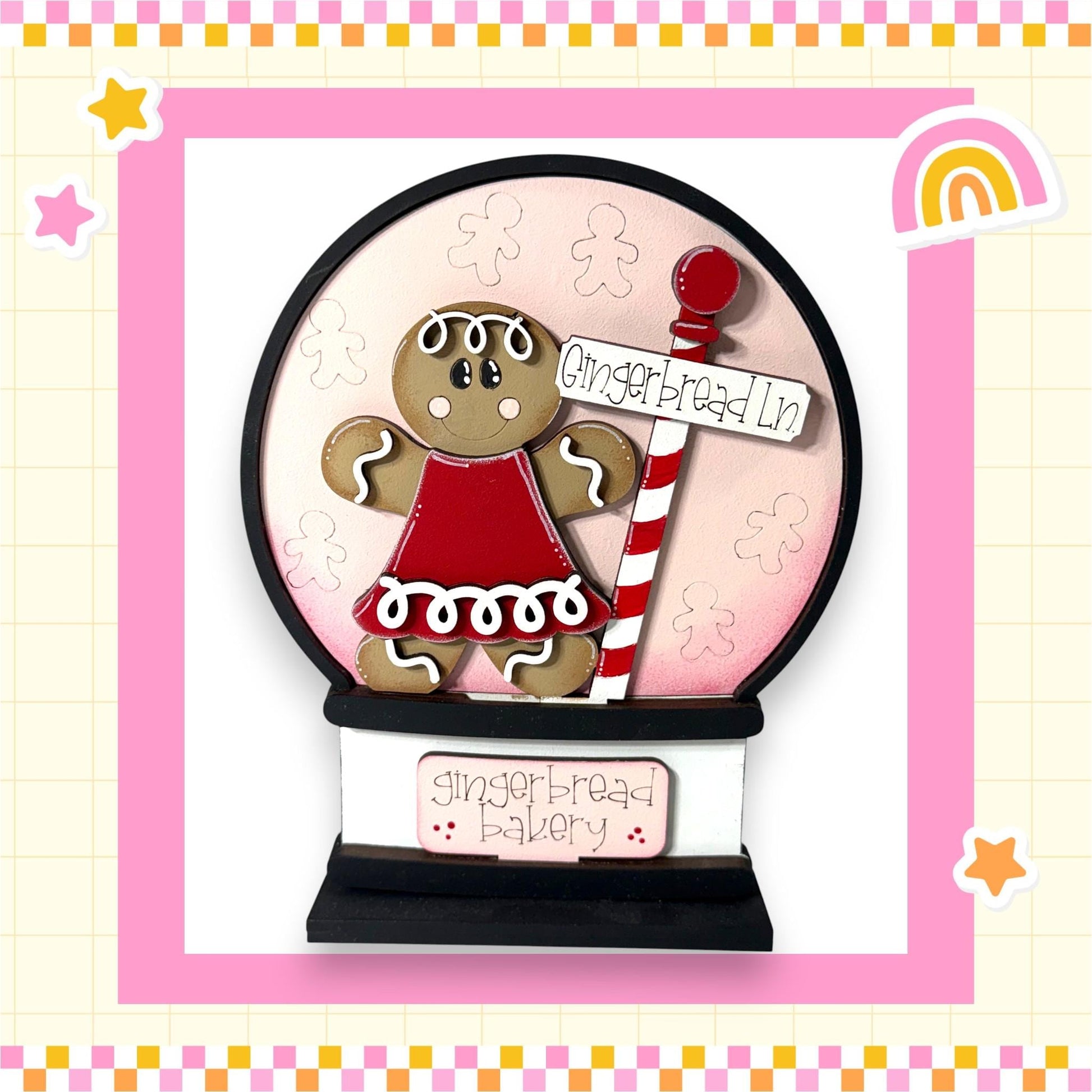 A gingerbread girl figurine is displayed in a snow globe, with a sign that reads "Gingerbread Lane" and a rainbow-colored background.
