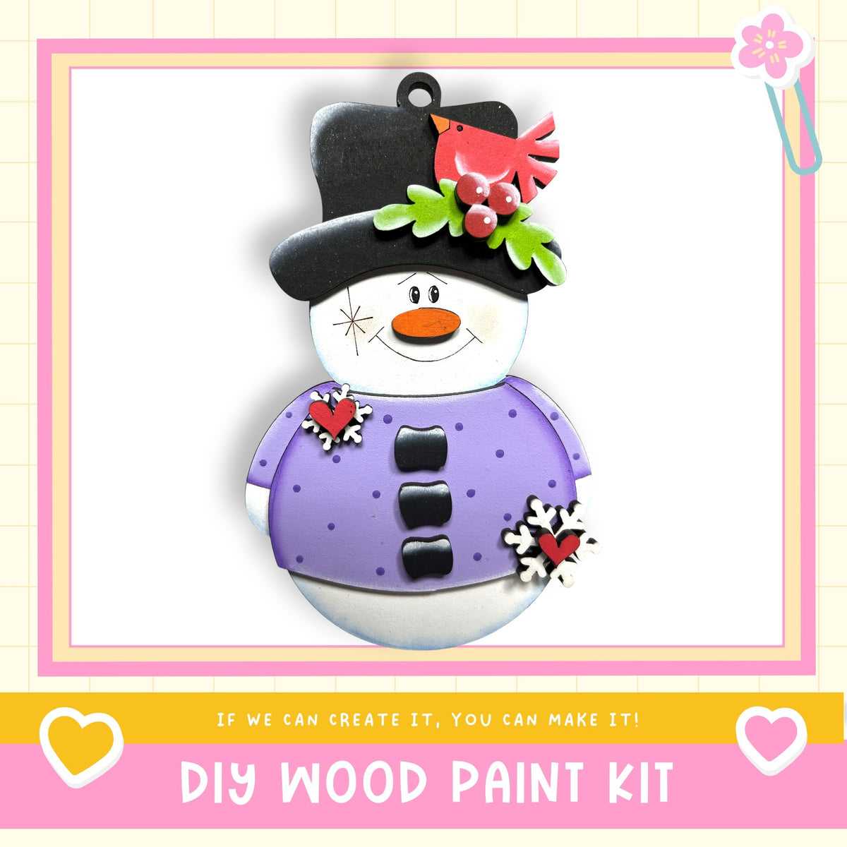 A snowman ornament with a black top hat, purple shirt, and red berries, along with a red bird perched on its head. The image is framed by a pink border and includes text that reads "DIY WOOD PAINT KIT" and "If we can create it, you can make it!"