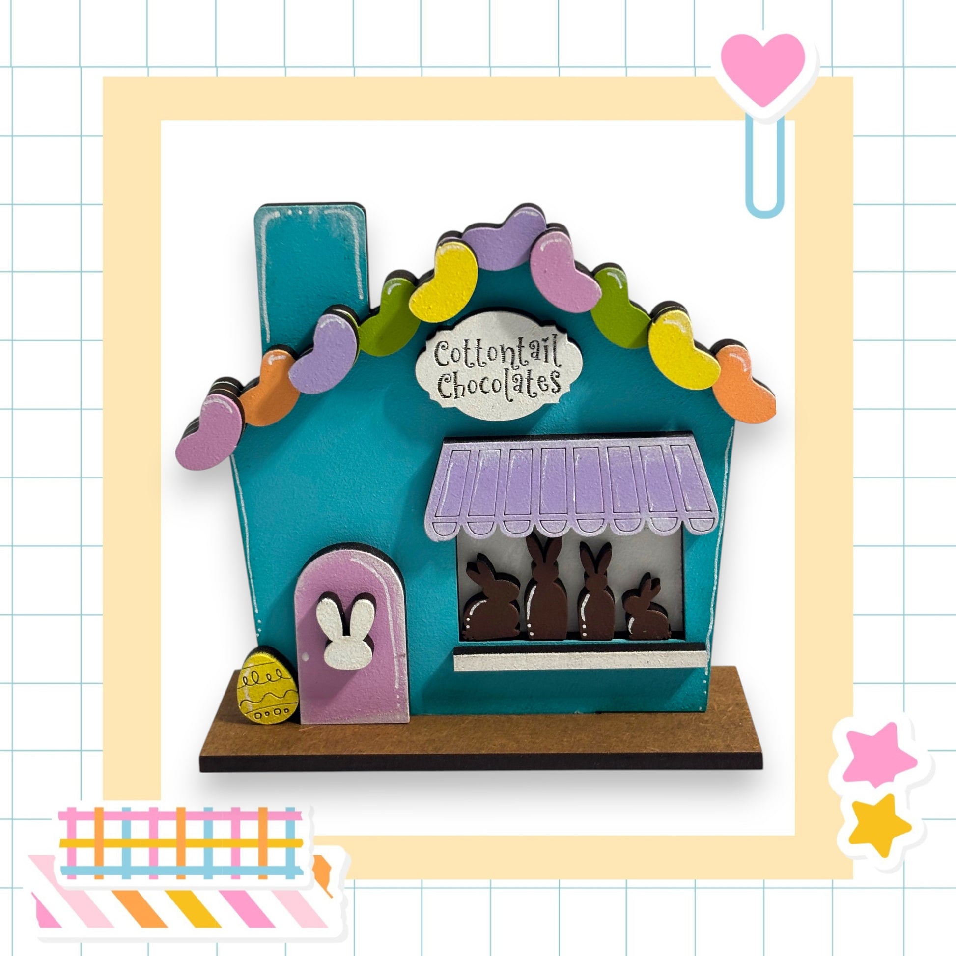 A colorful toy house with a sign that says "Cotton candy chocolates" on it, surrounded by Easter-themed decorations.