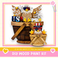 a DIY wood paint kit, with a wooden bucket and a smaller wooden basket containing various patriotic-themed decorations such as stars, flowers, and an eagle. The text "If we can create it, you can make it!" suggests that the kit is designed for individuals to create their own unique patriotic decorations.