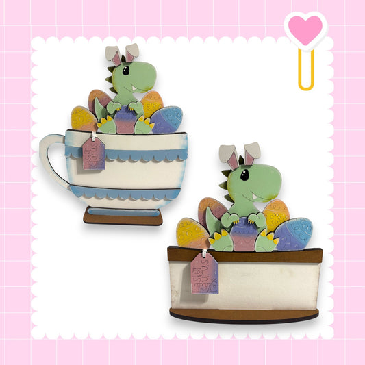 two cartoon dinosaur figures, one sitting inside a teacup and the other inside a cake dish, both with colorful decorations.