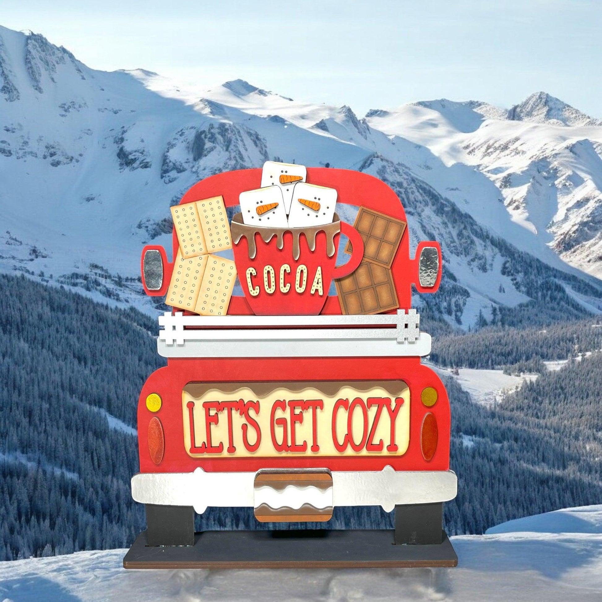 a red truck parked on top of a snow covered slope