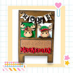 A wooden sign with moose heads and the text "Home" above them, along with the text "have a holly jolly Moosemas" below.