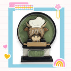 A wooden figurine of a cow wearing a chef's hat, sitting on a wooden table with the words "Moo CHEF" written on it.