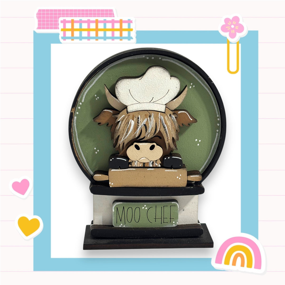 A wooden figurine of a cow wearing a chef's hat, sitting on a wooden table with the words "Moo CHEF" written on it.