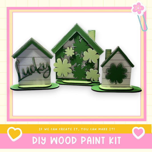 three small, green-colored houses with the word "Lucky" written on them, placed on a pink and yellow background.