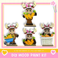 The image is a collage of four wooden animal figurines, each holding a carrot and wearing a bunny ear hat. The caption below the collage reads "DIY WOOD PAINT KIT" and "If we can create it, you can make it!"