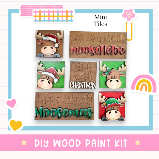 The image is a collage of six Christmas-themed wooden tiles, each featuring a moose wearing a hat and the text "We wish you a merry Christmas" or "Have a holly jolly Moosemas". The tiles are arranged in a grid pattern, with each tile displaying a different moose and holiday message.