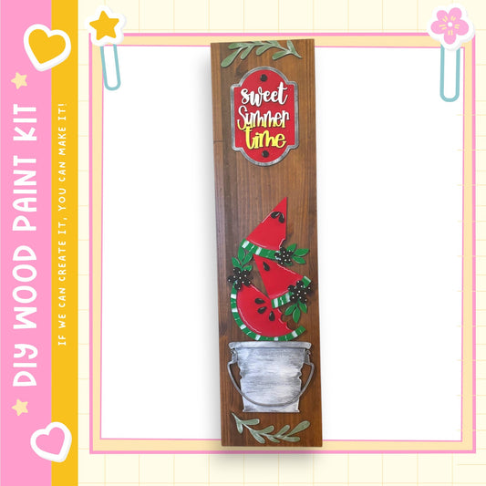 a wooden sign with a red and green design, including a red watermelon slice and green leaves, mounted on a wooden frame.