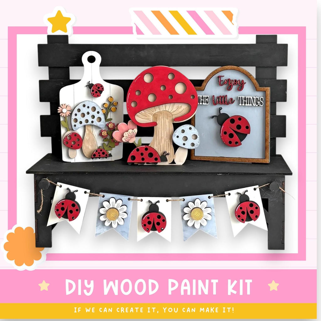The image is a DIY wood paint kit featuring a variety of wooden cutouts, including mushrooms, ladybugs, and flowers, arranged on a black shelf. The kit appears to be made of wood and is designed for painting.