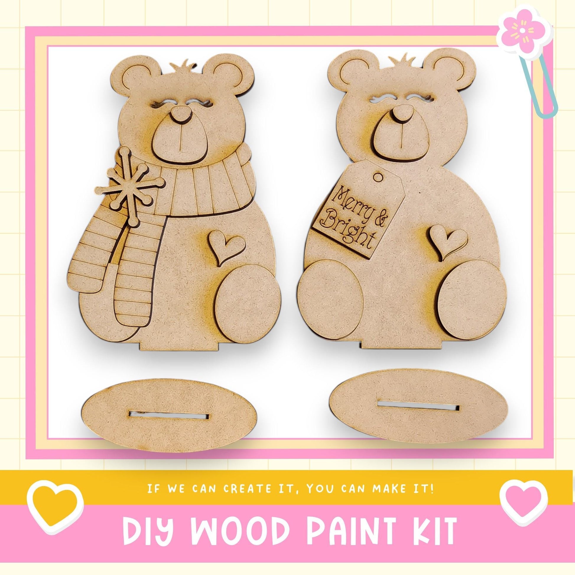 two wooden teddy bear ornaments, each with a tag that says "Merry & Bright". The ornaments are displayed against a pink and yellow background, and there is text at the bottom of the image that reads "DIY WOOD PAINT KIT" and "If we can create it, you can make it!".