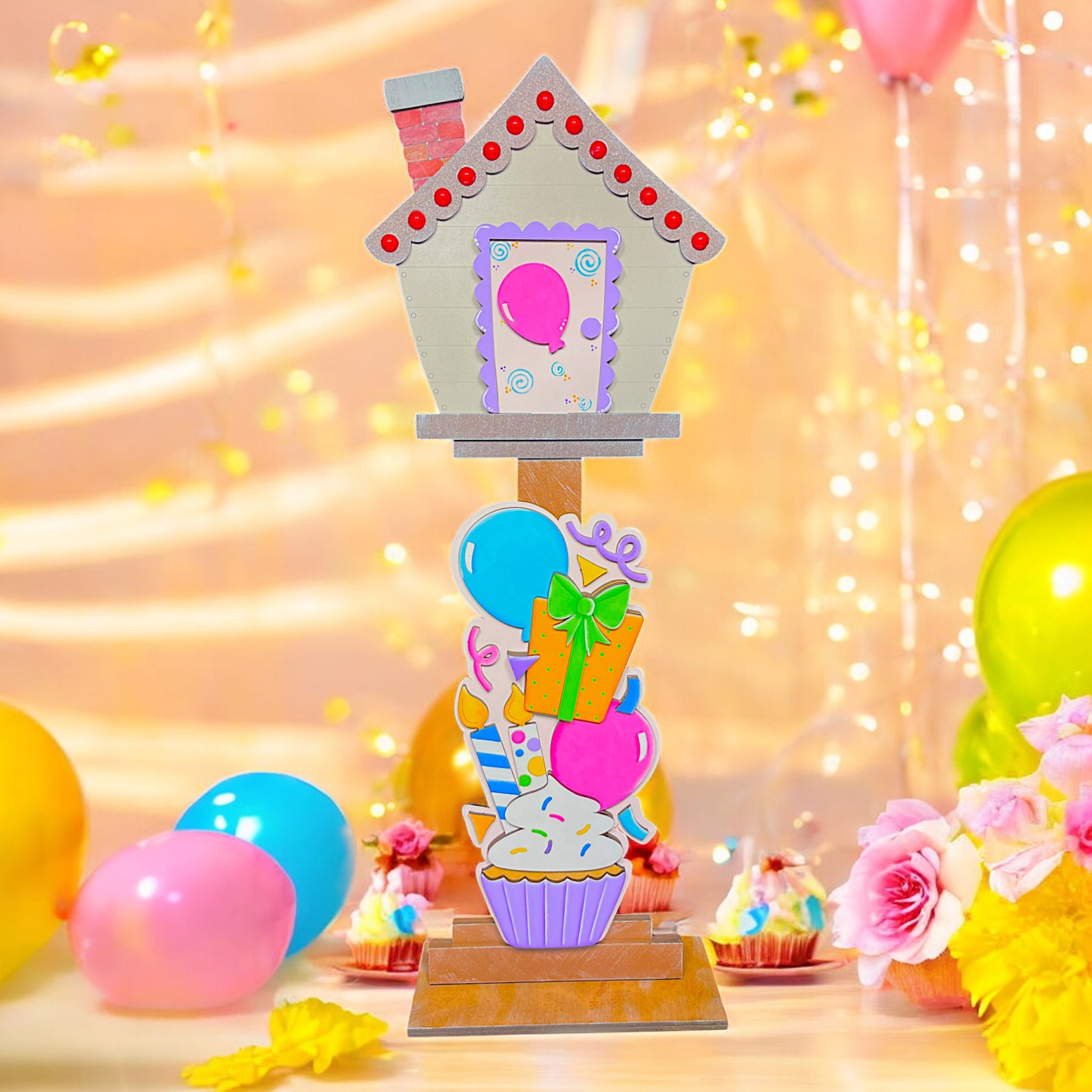 a cupcake with a house on top of it surrounded by balloons