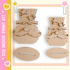 two wooden cutouts of cartoon-like characters, likely representing Santa Claus or a similar holiday figure, set against a pink and yellow background.