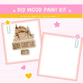 The image is a DIY wood paint kit with a pink background and a message encouraging creativity. It features a wooden Santa Claus figure and a blank white frame, along with decorative elements such as hearts and stars.