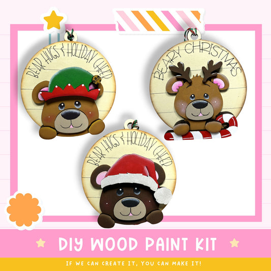 three wooden ornaments with bear faces, each wearing a different holiday-themed hat. The text on the ornaments reads "BEAR HUGS & HOLIDAY CHEER".