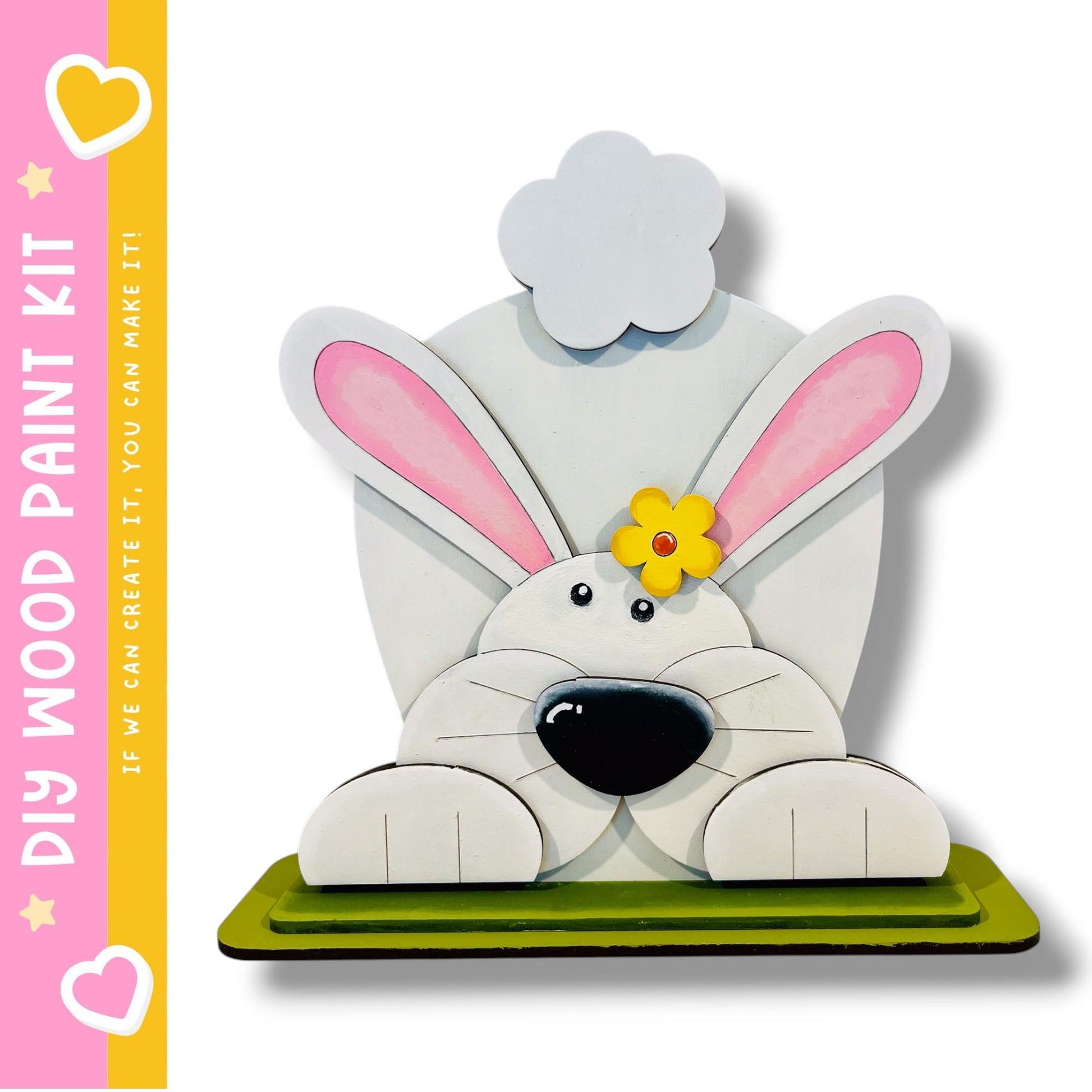 A wooden bunny sculpture with pink ears and a yellow flower on its head, sitting on a green base.