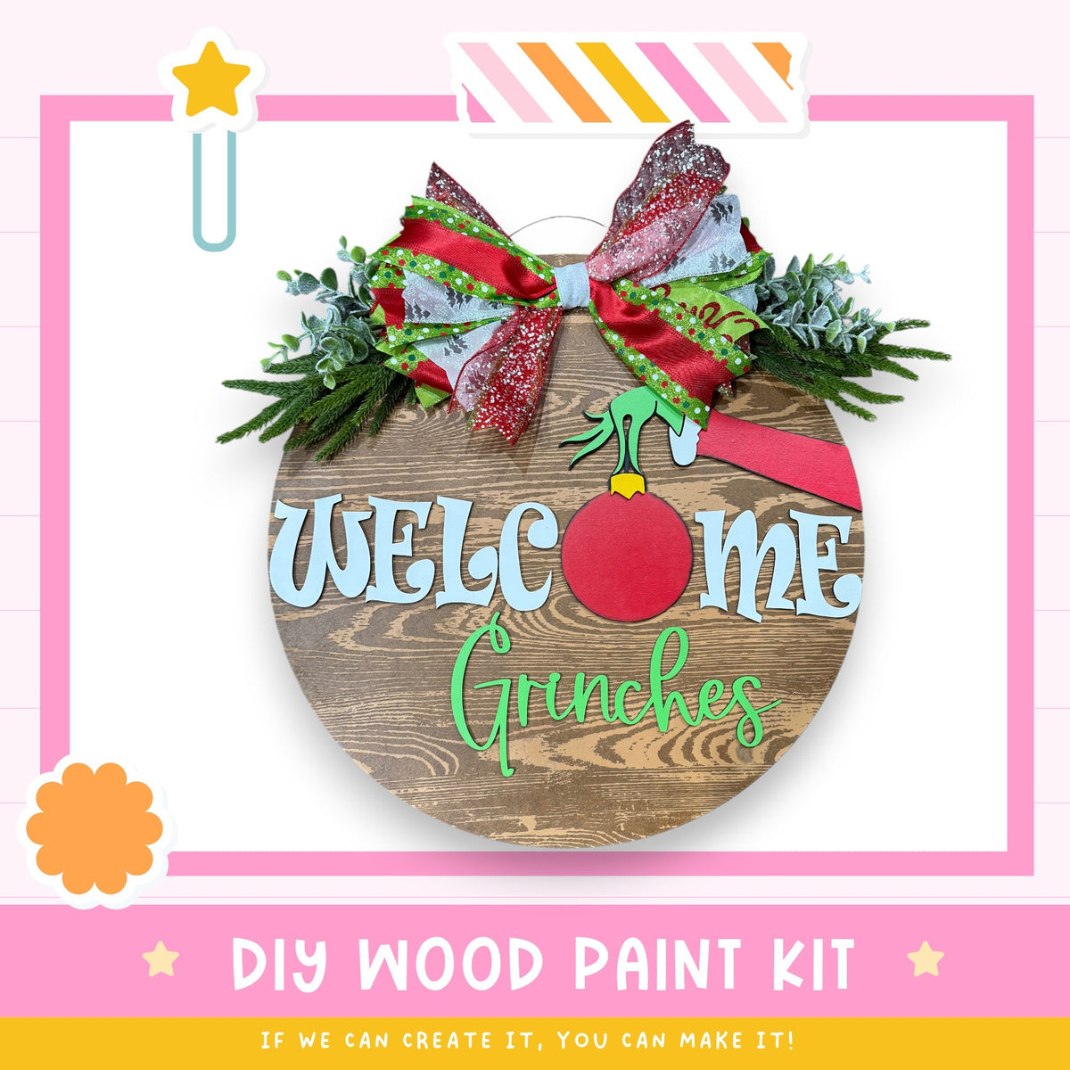 a DIY wood paint kit for creating a welcome sign with a Grinch-themed design. The kit includes a wooden sign with the text "Welcome Me Grinchies" and a bow made of red and green materials. The kit is presented in a pink and white color scheme, with a star decoration on the left side. The text "DIY WOOD PAINT KIT" is displayed at the bottom of the image, and the phrase "IF WE CAN CREATE IT, YOU CAN MAKE IT!" is written at the bottom right corner.