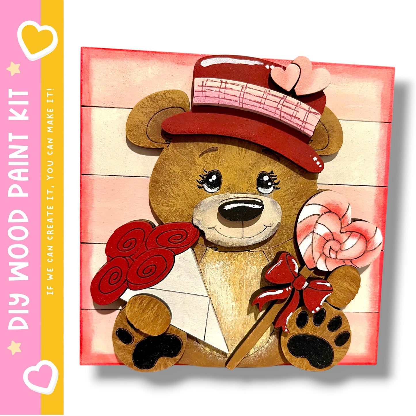 A wooden teddy bear holding a heart-shaped lollipop and a red bow, set against a pink background.