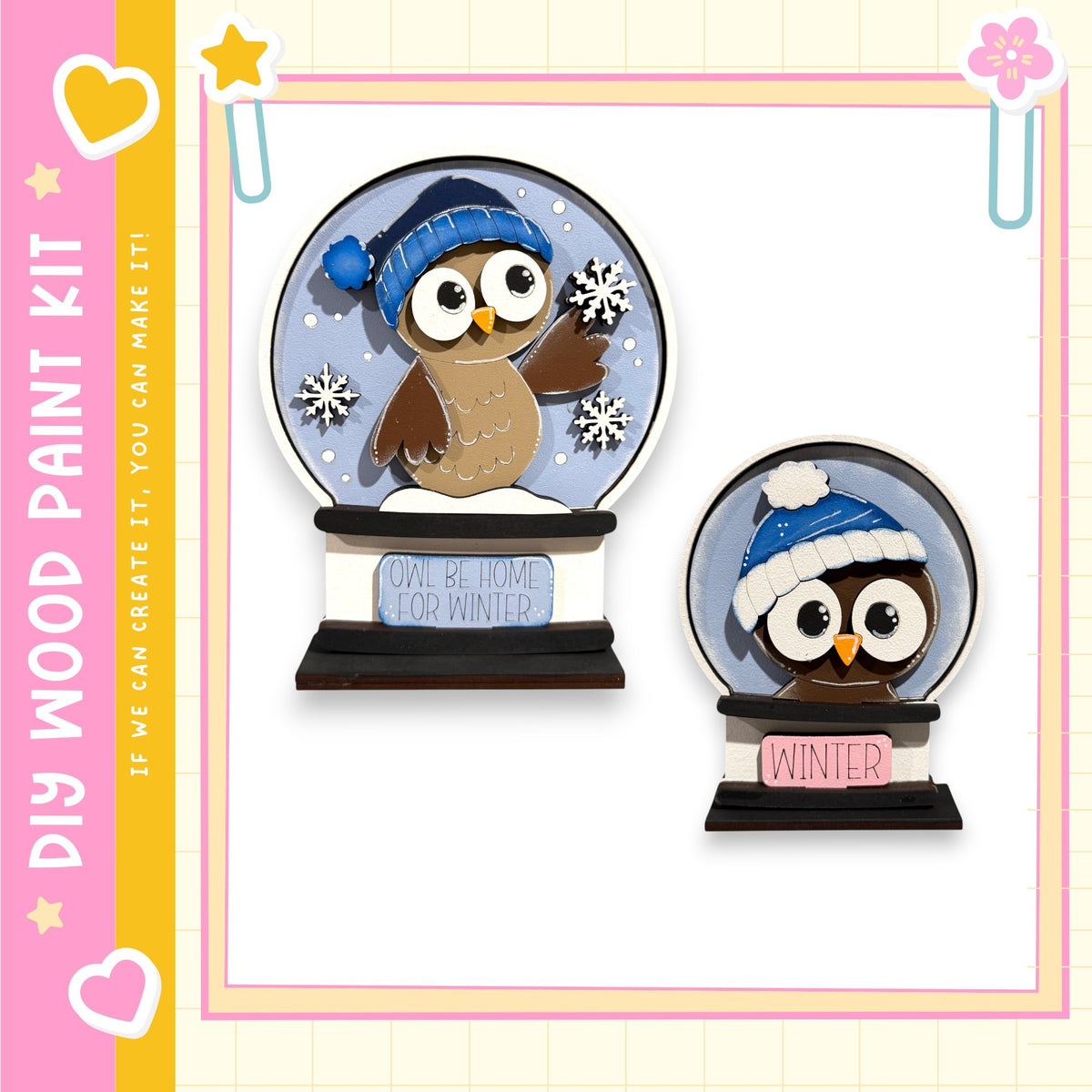 two snowglobe ornaments, each depicting an owl wearing a winter hat. The snowglobe on the left is larger and has a blue hat, while the one on the right is smaller and has a white hat. The snowglobes are set against a pink and yellow background, and the text "My Wood Paint Kit" is visible, suggesting that these ornaments are part of a kit for creating wooden decorations.