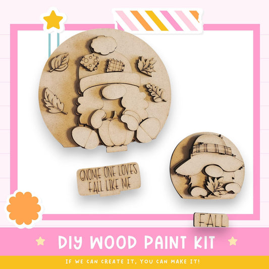The image is a DIY wood paint kit featuring two wooden gnome-shaped figures, one larger and one smaller, along with a sign that says "Gnome one loves fall like me". The kit appears to be designed for creating wooden gnome decorations or wall art.