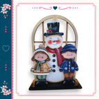 A snowman with two children standing beside it, all dressed in winter clothing.