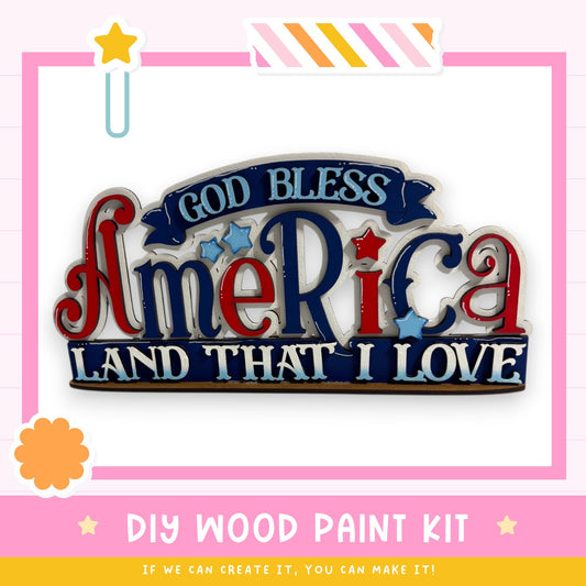 a DIY wood paint kit for creating a patriotic sign or decoration, with the text "God Bless America Land That I Love" prominently displayed.