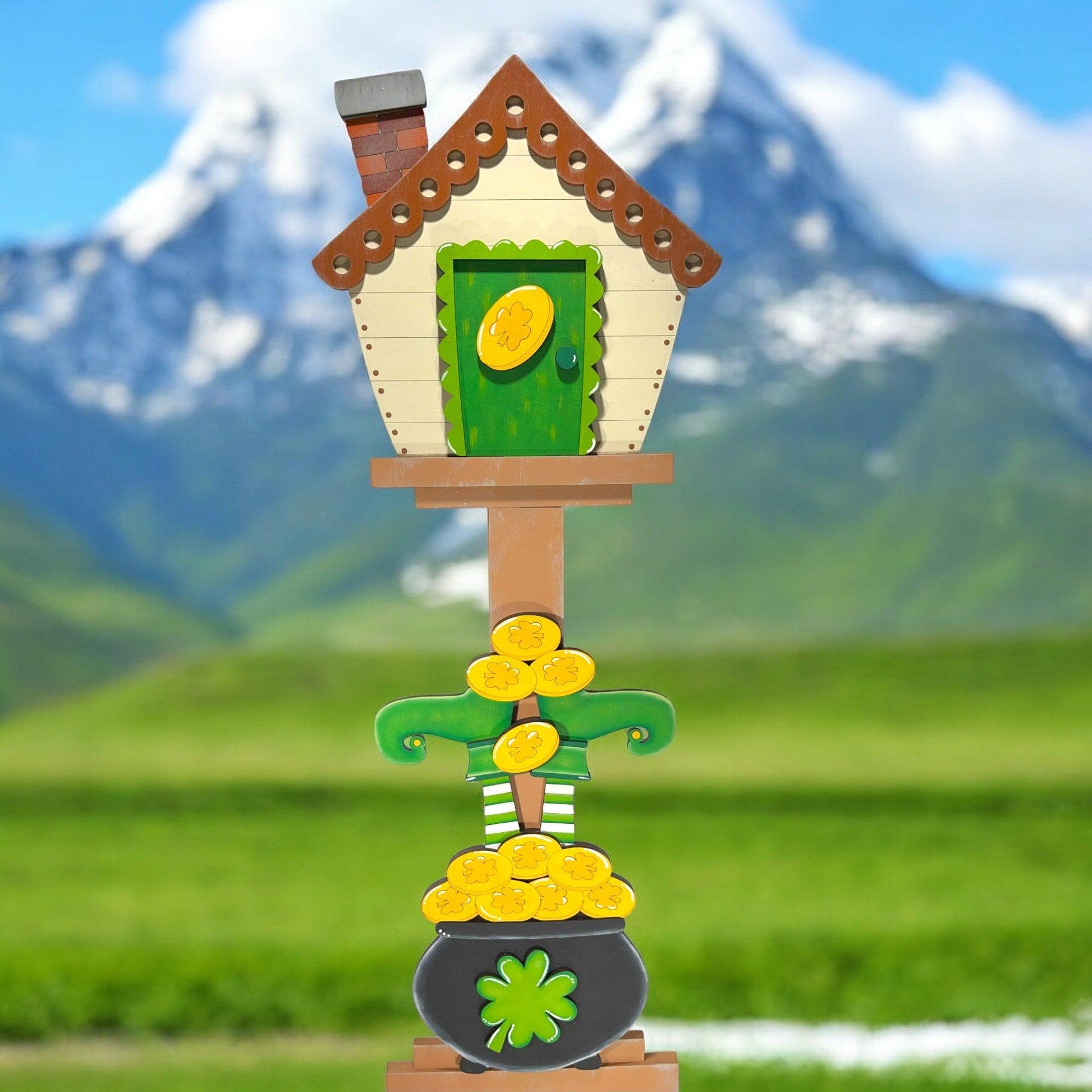 a birdhouse with a pot of gold coins on top of it