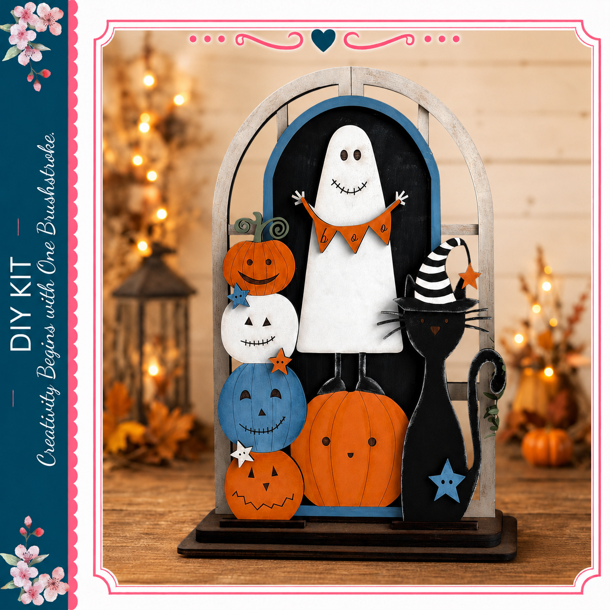 A Halloween-themed DIY kit featuring a ghost, a cat, and various pumpkins and jack-o-lanterns. The kit is displayed on a wooden surface, with a blurred background that includes a lantern and other Halloween decorations.
