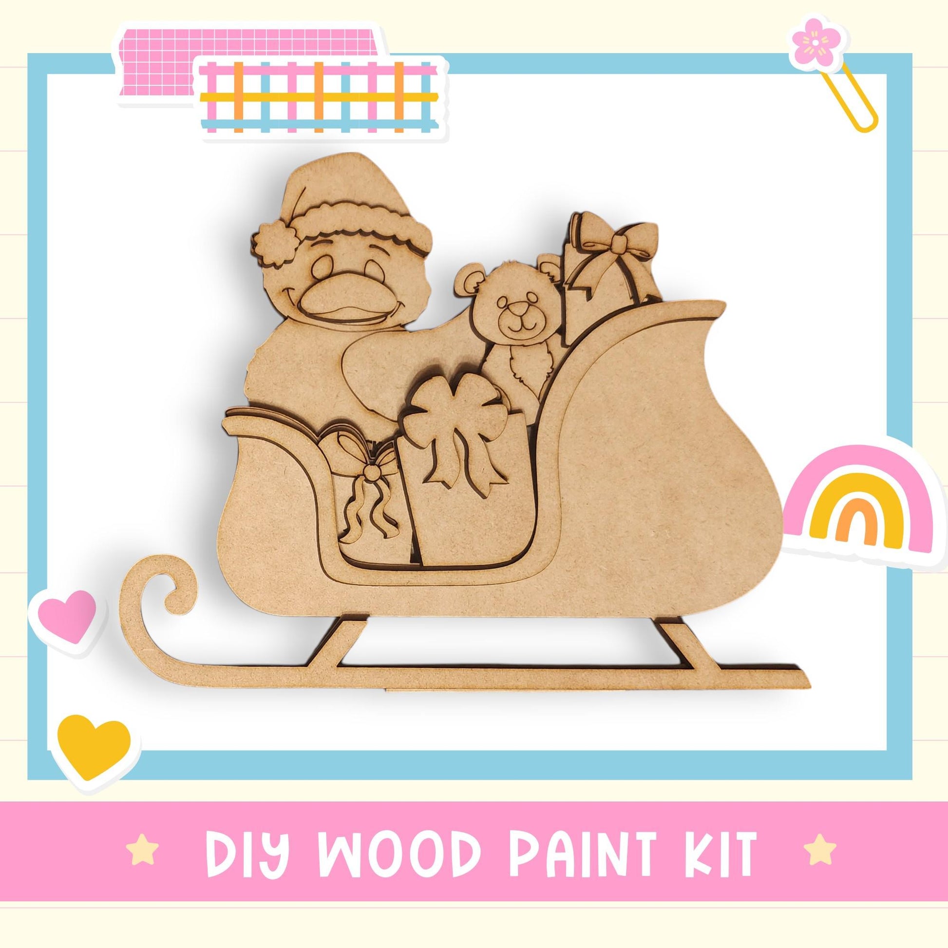 The image is a DIY wood paint kit featuring a wooden Santa Claus figure sitting on a sled, holding presents and a teddy bear.