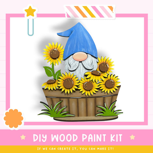 A gnome wearing a blue hat is sitting in a wooden planter filled with yellow sunflowers.
