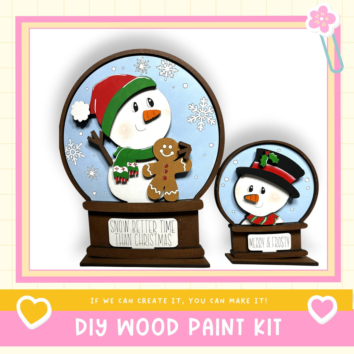 two snowglobe-like decorations, one larger and one smaller, both with a snowman and a gingerbread man figure. The larger snowglobe is placed on a brown base, while the smaller one is on a brown stand. The decorations are set against a snowy background with snowflakes. The image also includes text that reads "If we can create it, you can make it!" and "DIY WOOD PAINT KIT".