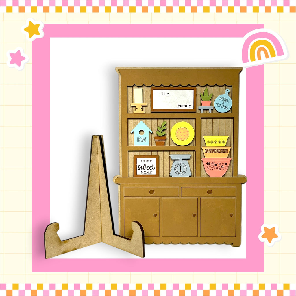 A wooden hutch with various knick-knacks and decorations, including a sign that says "The Family" and a rainbow-colored frame.