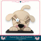 A wooden dog figurine with a flower in its eye, sitting on a black base.