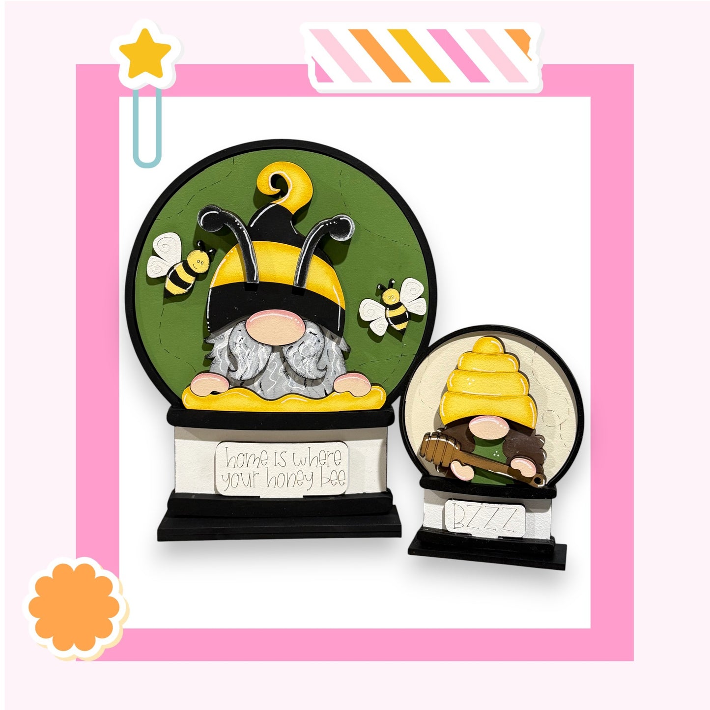 two gnomes, one larger and one smaller, both wearing yellow hats and holding honeycombs. The larger gnome is positioned in the center of the image, while the smaller gnome is located to the right. The background of the image is green, and there is a sign that reads "home is where your honey bee" in the bottom left corner.