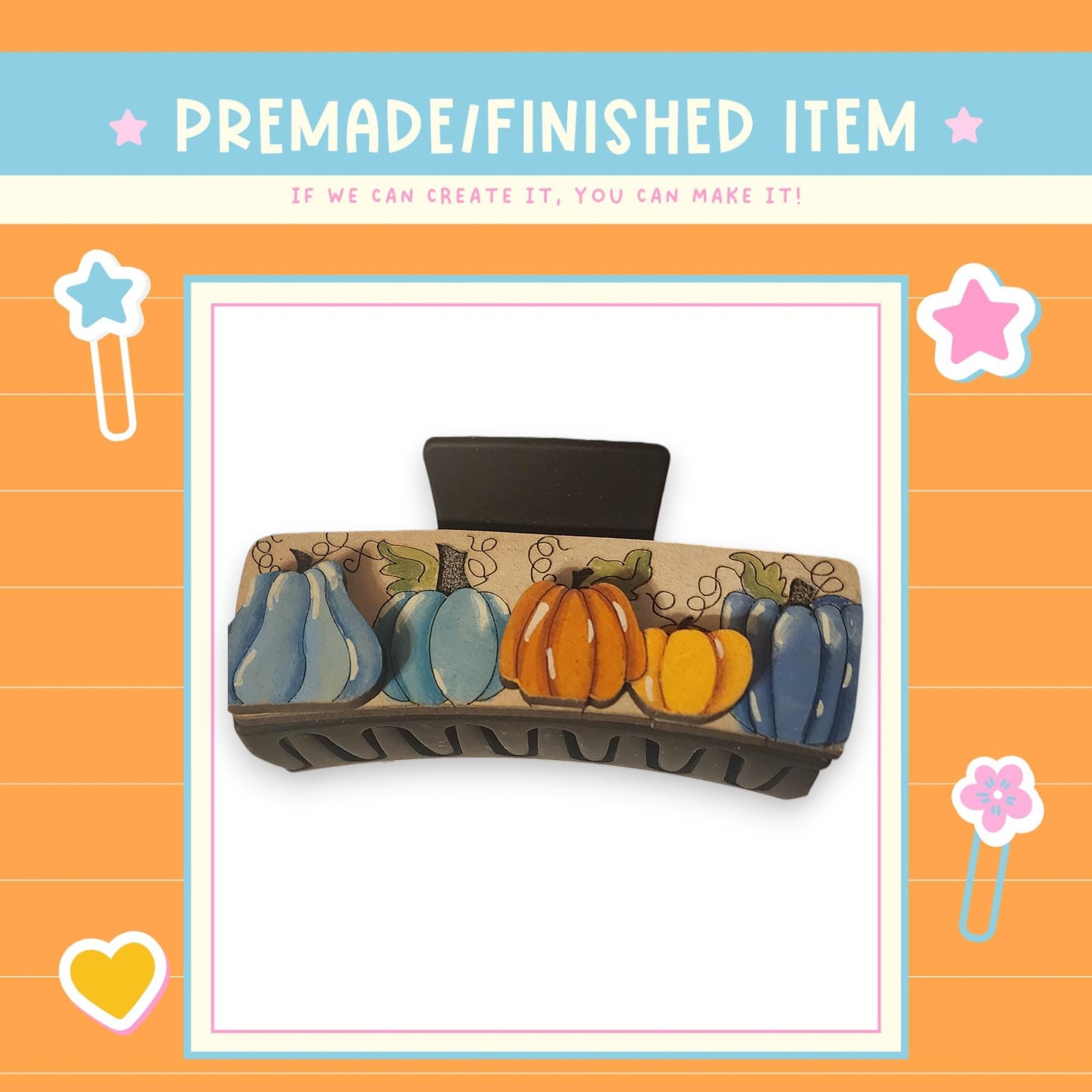 a decorative hair clip with a pumpkin and leaf design on it, surrounded by a colorful border with stars and hearts.