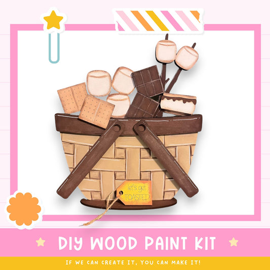 The image is a colorful illustration of a DIY wood paint kit, featuring a basket filled with various art supplies such as crayons, paintbrushes, and a star. The text "DIY WOOD PAINT KIT" is prominently displayed, along with the phrase "If we can create it, you can make it!" indicating that the kit is designed for creative individuals to make their own art supplies.