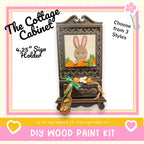 The image is a promotional poster for a DIY wood paint kit, featuring a wooden cabinet with a picture of a rabbit and carrots on it. The text on the poster includes the product name, a description of the product, and a call to action to create the product.