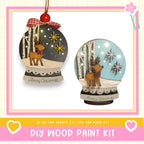 two Christmas ornaments, each with a unique design and a red bow. The ornaments are displayed against a white background, and there is text at the bottom of the image that reads "DIY WOOD PAINT KIT" and "IF WE CAN CREATE IT, YOU CAN MAKE IT!"