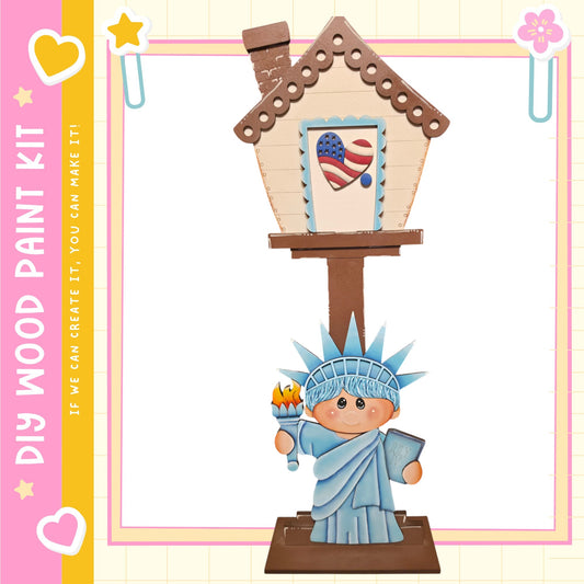 A wooden house with a painted American flag on the front, featuring a small statue of the Statue of Liberty.