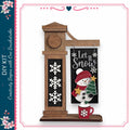 A wooden clock with a snowman decoration on it, along with a sign that says "Let it snow".