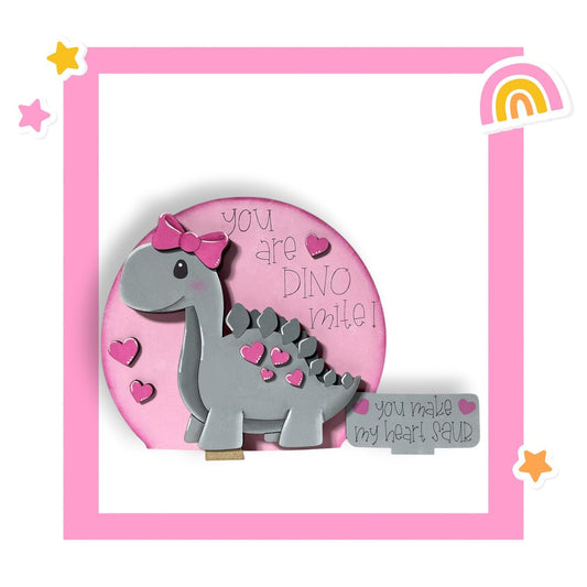 a pink and gray brooch with a dinosaur on it